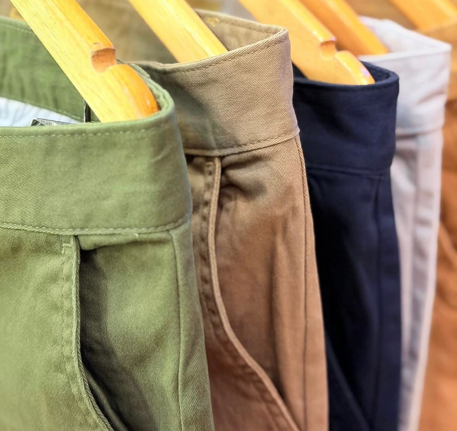 Snooze chino waistbands in olive, tan, navy and stone lined up on wooden hangers