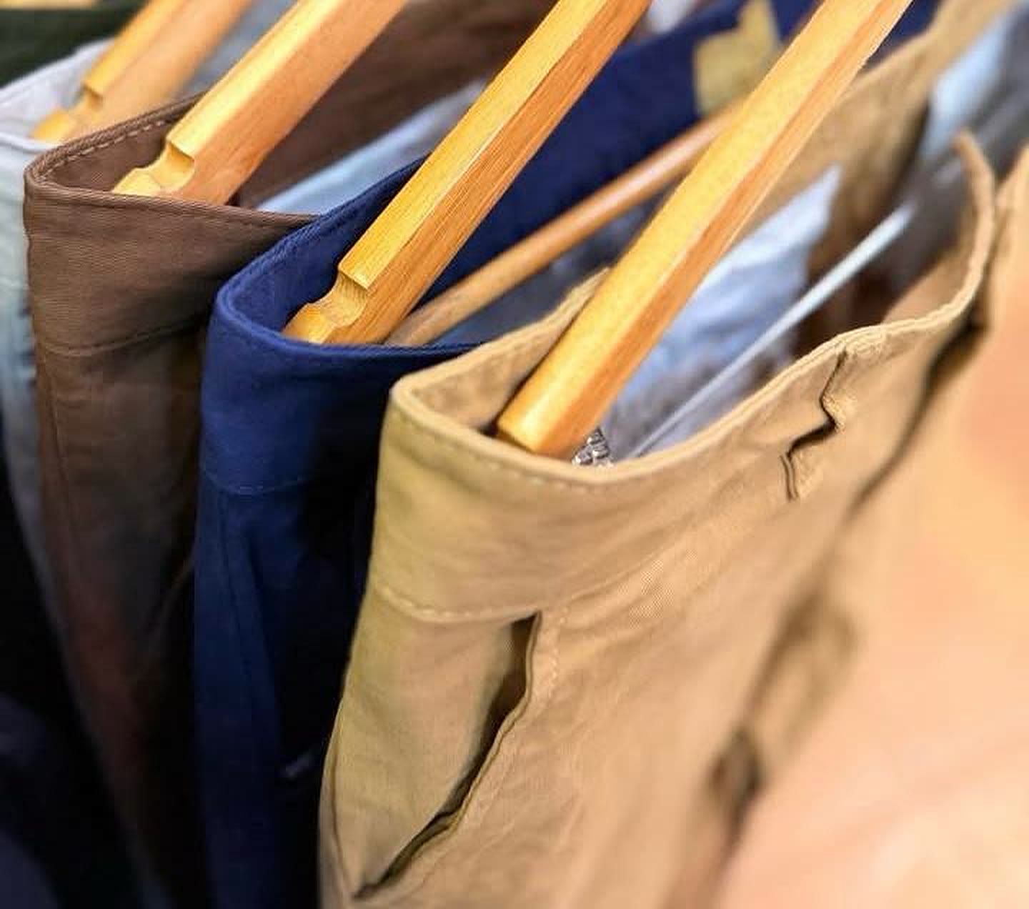 Snooze chinos in brown, navy and tan on wooden hangers, waistband detail